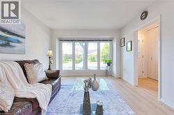 Spacious room featuring light wood-finish flooring, a bright bay window, crisp white walls, and a recessed entryway with a white paneled door - 