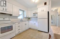 Bright, updated kitchen featuring white cabinetry with brushed nickel hardware, stainless steel appliances including a double wall oven and refrigerator, subway tile backsplash, and light wood-finish - 