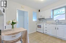 Kitchen with white cabinetry, tile backsplash, laminate countertops, and a window above the sink - 