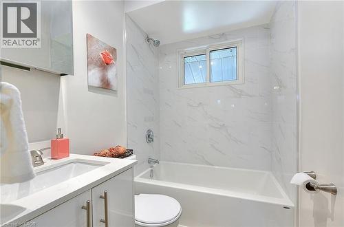 Bathroom featuring a white vanity with an undermount sink, a coordinating white countertop, and a built-in bathtub with a shower - 245 West 33Rd Street, Hamilton, ON - Indoor Photo Showing Bathroom