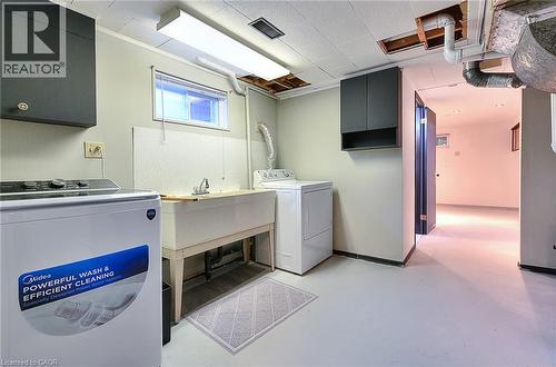 Laundry area featuring a utility sink, wall-mounted cabinetry, and window - 245 West 33Rd Street, Hamilton, ON - Indoor Photo Showing Laundry Room