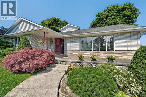 Exterior featuring a blend of brick and horizontal siding, a covered front entry, concrete walkway, and established landscaping - 134 Russ Road, Grimsby, ON - Outdoor