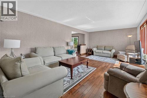 Spacious living area featuring wood-finish flooring, textured wall finishes, white crown molding, and large windows with vertical blinds - 134 Russ Road, Grimsby, ON - Indoor Photo Showing Living Room