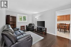 Living area featuring dark wood-finish flooring, light gray wall paint, and a bright white window frame - 