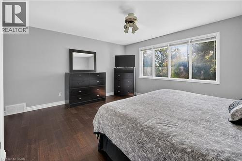 Spacious room featuring wood-finish flooring, light grey walls, and a multi-pane window framing exterior trees - 134 Russ Road, Grimsby, ON - Indoor Photo Showing Bedroom