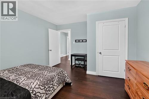 Bedroom featuring light blue walls, dark wood-finish flooring, white baseboards, and a white paneled door - 134 Russ Road, Grimsby, ON - Indoor Photo Showing Bedroom