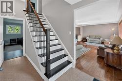 Staircase featuring dark wood-finish treads, white risers, and wrought iron balusters with a wood-finish handrail - 
