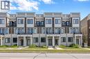 Modern townhome exterior featuring brick and stone cladding, multiple balconies with glass railings, large windows with dark frames, and covered front entrances with architectural columns - 1451 Green Road, Bowmanville, ON  - Outdoor With Facade 