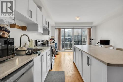 Open-concept kitchen featuring white cabinetry, light-toned countertops, a stainless steel sink with a gooseneck faucet, and light wood-finish flooring - 1451 Green Road, Bowmanville, ON - Indoor Photo Showing Kitchen With Upgraded Kitchen