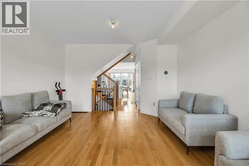 Open-concept living area featuring wood-finish flooring, a contemporary staircase with wood handrails and black balusters, and recessed ceiling lighting - 1451 Green Road, Bowmanville, ON - Indoor Photo Showing Living Room
