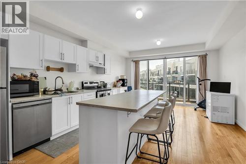 Open-concept kitchen featuring white cabinetry, stainless steel appliances, a center island with seating, and wood-finish flooring - 1451 Green Road, Bowmanville, ON - Indoor Photo Showing Kitchen With Upgraded Kitchen