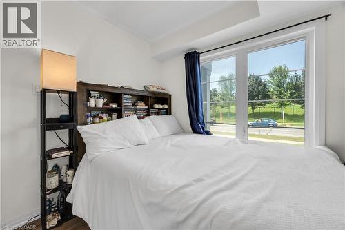 Bright room featuring a large window with white framing, blue drapes, and a built-in wooden headboard with shelving - 1451 Green Road, Bowmanville, ON - Indoor Photo Showing Bedroom