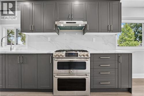 Contemporary kitchen featuring dark gray shaker cabinetry, white countertops, and a white tile backsplash with subtle veining - 36 Mahony Avenue, Hamilton, ON - Indoor Photo Showing Kitchen With Upgraded Kitchen