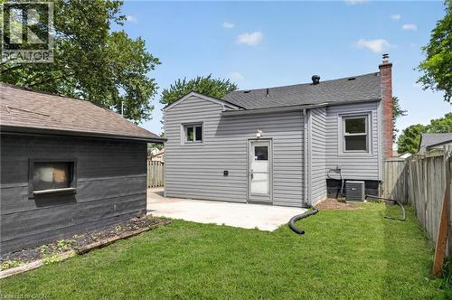 Rear exterior featuring gray horizontal siding, a brick chimney, and a concrete patio - 36 Mahony Avenue, Hamilton, ON - Outdoor With Exterior