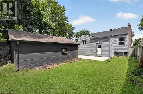 Expansive backyard featuring a manicured lawn, concrete patio, and a detached structure with a pitched roof - 36 Mahony Avenue, Hamilton, ON - Outdoor