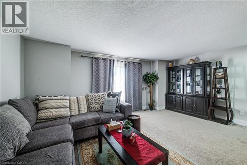 Spacious living area featuring light gray wall tones, a textured ceiling, and light-toned carpeting - 233 Red Clover Court, Kitchener, ON - Indoor Photo Showing Living Room