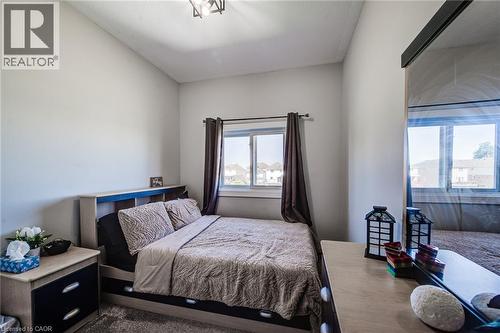Bedroom featuring a window with dark drapes, light gray walls, and a contemporary ceiling light fixture - 233 Red Clover Court, Kitchener, ON - Indoor Photo Showing Bedroom