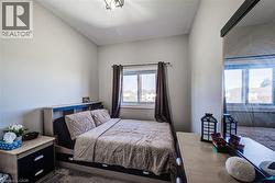 Bedroom featuring a window with dark drapes, light gray walls, and a contemporary ceiling light fixture - 