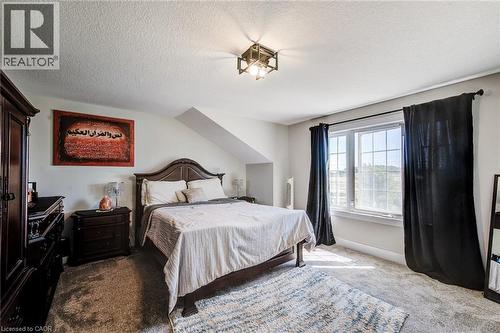 Carpeted room with a multi-pane window, sloped ceiling feature, and an overhead geometric light fixture - 233 Red Clover Court, Kitchener, ON - Indoor Photo Showing Bedroom