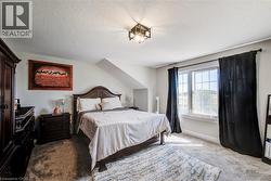 Carpeted room with a multi-pane window, sloped ceiling feature, and an overhead geometric light fixture - 