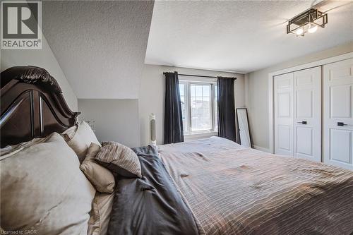 Bedroom featuring a window with natural light, two paneled closet doors with dark hardware, and a contemporary ceiling light fixture - 233 Red Clover Court, Kitchener, ON - Indoor Photo Showing Bedroom