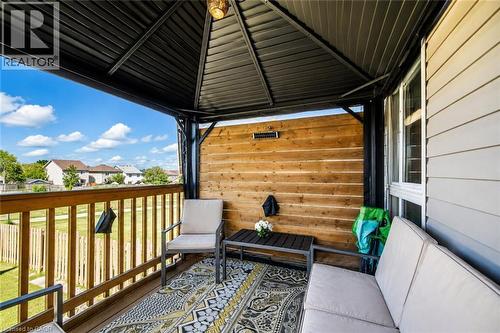 Covered outdoor patio featuring a slatted wood privacy wall, a black metal gazebo roof, and light-colored siding - 233 Red Clover Court, Kitchener, ON - Outdoor With Deck Patio Veranda With Exterior
