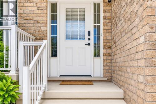 Exterior entrance featuring light-toned brickwork and a white entry door with frosted glass side lights - 233 Red Clover Court, Kitchener, ON - Outdoor With Exterior