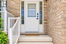 Exterior entrance featuring light-toned brickwork and a white entry door with frosted glass side lights - 233 Red Clover Court, Kitchener, ON  - Outdoor With Exterior 