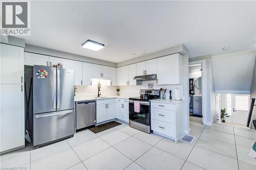 Kitchen featuring white cabinetry, stainless steel appliances, a white tile backsplash, and a modern ceiling light fixture - 233 Red Clover Court, Kitchener, ON - Indoor Photo Showing Kitchen With Stainless Steel Kitchen