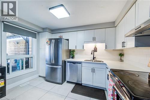 Kitchen featuring white shaker-style cabinetry, stainless steel appliances, a white subway tile backsplash, and a white countertop - 233 Red Clover Court, Kitchener, ON - Indoor Photo Showing Kitchen With Stainless Steel Kitchen With Double Sink