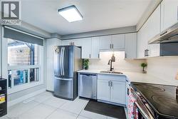 Kitchen featuring white shaker-style cabinetry, stainless steel appliances, a white subway tile backsplash, and a white countertop - 