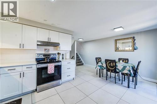 Modern kitchen featuring white shaker cabinetry, stainless steel appliances, a subway tile backsplash, and light-toned tile flooring - 233 Red Clover Court, Kitchener, ON - Indoor Photo Showing Kitchen