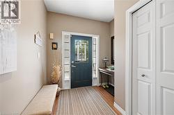 Entryway featuring a dark paneled door with decorative glass inserts, sidelight windows, and wood-finish flooring - 
