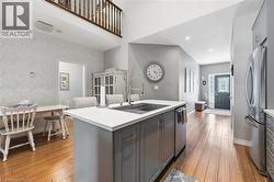 Kitchen island featuring grey cabinetry, a white countertop, and a stainless steel sink with a gooseneck faucet - 