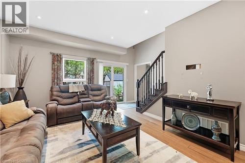 Open living space featuring wood-finish flooring, recessed lighting, and a prominent staircase with dark wood railings - 10 Kopperfield Lane, Hamilton, ON - Indoor Photo Showing Living Room