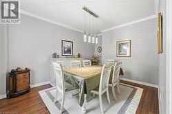 Dining area featuring wood-finish flooring, a contemporary linear pendant light fixture, and crown molding - 