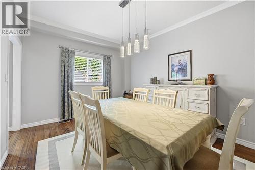 Dining area featuring wood-finish flooring, a contemporary linear chandelier, window treatments, and crown molding - 10 Kopperfield Lane, Hamilton, ON - Indoor