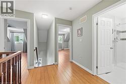 Upper-level hallway featuring wood-finish flooring, light gray wall paint, and white trim - 