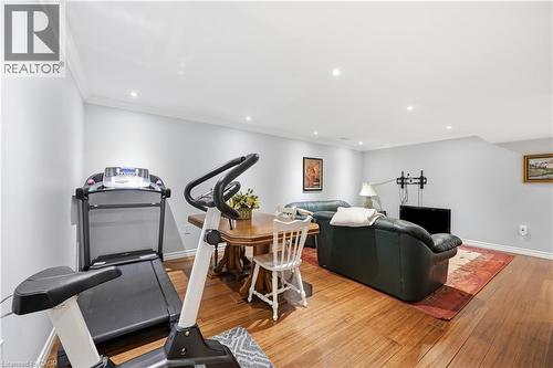Hardwood flooring throughout a versatile open-concept space featuring recessed lighting, crown molding, and painted walls - 10 Kopperfield Lane, Hamilton, ON - Indoor Photo Showing Gym Room