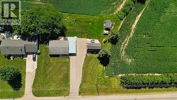 Aerial property overview featuring two residential structures, extensive green space, and a large cultivated field - 