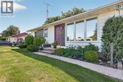 White siding exterior with a dark red entry door, a prominent front picture window, and a concrete pathway leading to the entry - 