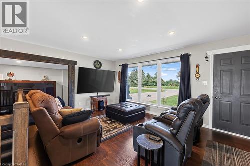 Living area featuring dark wood-finish flooring, a large multi-pane window, recessed lighting, and a dark paneled entry door - 184726 Cornell Road, Tillsonburg, ON - Indoor Photo Showing Living Room