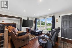 Living area featuring dark wood-finish flooring, a large multi-pane window, recessed lighting, and a dark paneled entry door - 