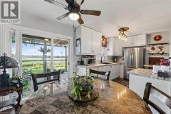 Kitchen area featuring white cabinetry, stainless steel appliances, and a central ceiling fan - 