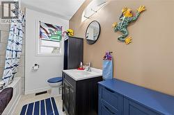 Bathroom featuring a white bathtub with tiled surround, a built-in vanity with a white countertop and rectangular sink, a wall-mounted mirror, a window with a decorative panel, and light-toned wall pa - 