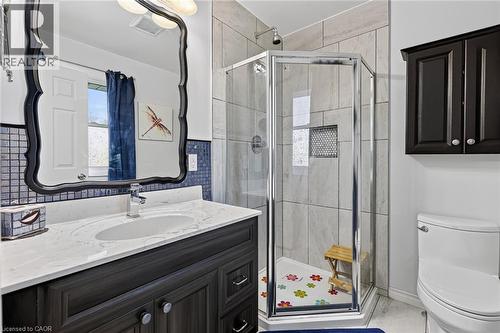 Bathroom featuring a corner glass-enclosed shower with tile surround, a dark wood-finish vanity with an undermount sink, a white countertop, and a decorative framed mirror - 184726 Cornell Road, Tillsonburg, ON - Indoor Photo Showing Bathroom