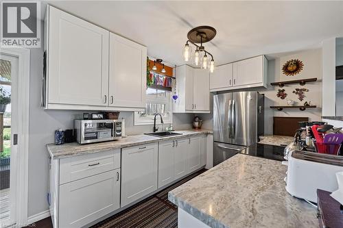 Kitchen featuring ample white shaker cabinetry, speckled countertops, stainless steel refrigerator, and black sink with a matte black faucet - 184726 Cornell Road, Tillsonburg, ON - Indoor Photo Showing Kitchen