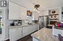 Kitchen featuring ample white shaker cabinetry, speckled countertops, stainless steel refrigerator, and black sink with a matte black faucet - 184726 Cornell Road, Tillsonburg, ON  - Indoor Photo Showing Kitchen 