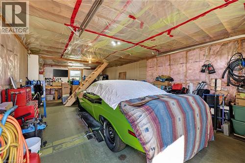 Expansive garage space featuring exposed wood framing, ceiling insulation, and a built-in wooden staircase - 184726 Cornell Road, Tillsonburg, ON - Indoor