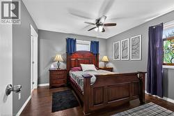 Spacious room featuring wood-finish flooring, a ceiling fan with integrated lighting, and multiple windows - 